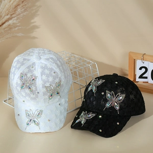 Detail of white and black lace baseball caps with sparkling rhinestone butterfly patterns