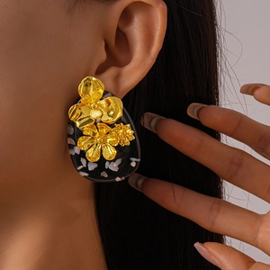 Close-up of vintage resin oval earring with golden 3D flower detailing on a model
