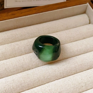 Macro detail of a vintage wide resin ring with emerald green marble texture on a velvet tray