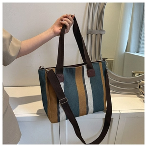 Detail of striped canvas tote with brown handles and adjustable shoulder strap