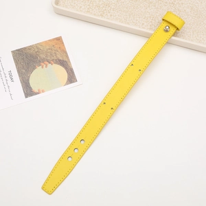 Detail of yellow faux leather wrist strap with silver rivet and fine stitching