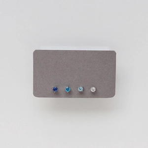 Close-up of four claw-set birthstone stud earrings in shades of blue and clear white