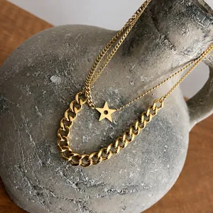 Close-up of double layer gold star pendant necklace on rustic grey ceramic vessel
