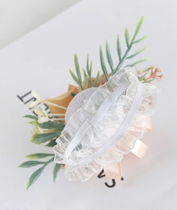 Detail of wedding wrist corsage showing the elastic lace band and peach faux flower