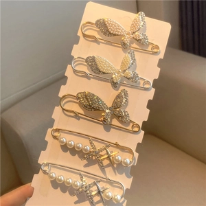 Five decorative pearl and rhinestone brooches with butterfly and starfish designs on a card