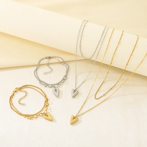 Detail of layered gold and silver heart necklaces and bracelets on beige background