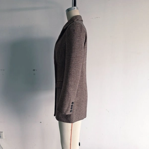 Detail view of houndstooth plaid coat sleeve featuring four black decorative buttons