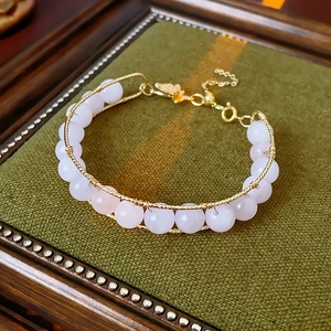 Detailed view of pink crystal bead bracelet with gold wire wrap and leaf pendant detail