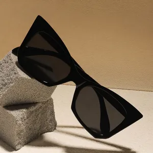Occhiali da sole cat-eye neri retrò con montatura geometrica spessa su pietra