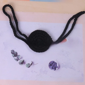 Detailed close-up of a handmade black crochet nose ornament for Halloween party props