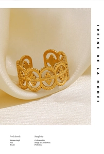 Close-up of golden adjustable ring with geometric hollow relief on white silk
