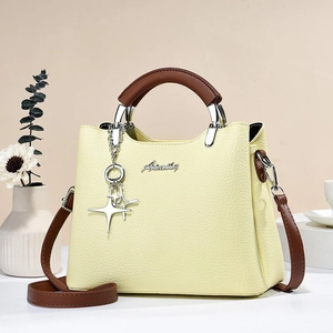 Detail of light yellow lychee pattern bucket bag with brown handles and a star charm