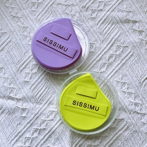 Macro detail of purple and green makeup sponges in clear cases on knit fabric