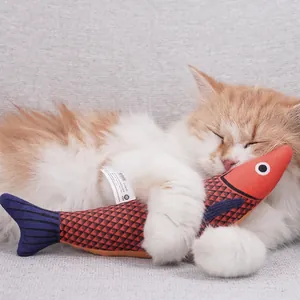 Realistic koi fish catnip toy shown with a sleeping cat on a cozy gray sofa