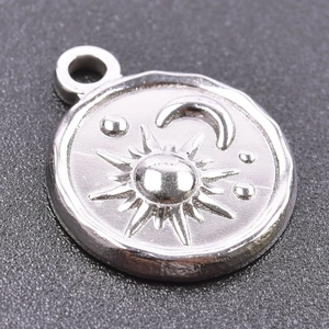 Macro detail of silver stainless steel round pendant with sun and moon relief carving
