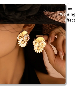 Close-up of elegant gold daisy earrings with white enamel petals on a model