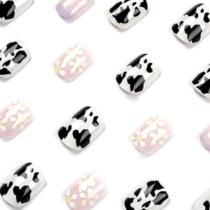 Short square press-on nails with purple French tips, cow print and daisy patterns
