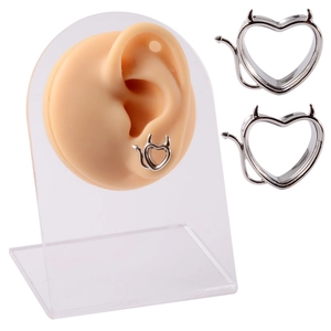 Silver stainless steel heart ear gauges with devil horns on a silicone ear model