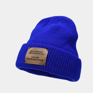 Detailed view of Klein blue knit beanie featuring a brown fabric patch and soft texture