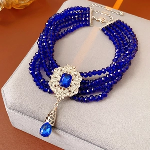 Detail view of multi-layer navy beaded necklace with vintage silver pendant and blue drop charm