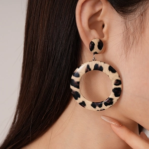 Detail view of large leopard print hoop earrings worn by a model for a stylish look