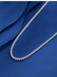 Macro detail of silver S925 moissanite tennis necklace on premium blue fabric background