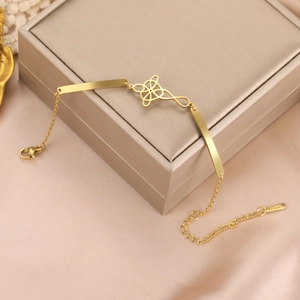 Close-up of golden stainless steel bracelet with floral charm and lobster clasp detail
