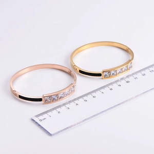 Detailed view of luxury gold and rose gold crystal bangles with a measurement ruler