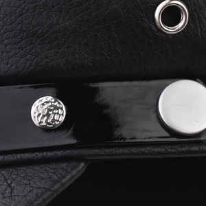 Close-up of black pebbled leather texture with silver decorative buttons and metal eyelet