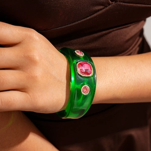 Detail of green resin cuff bracelet with pink crystal stones and rhinestones on wrist
