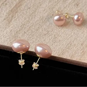 Detail of pink pearl earrings with gold posts on a black velvet jewelry display box