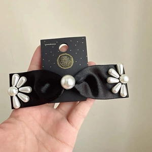 Barrette en satin noir élégante avec fleurs de perles délicates sur carte de luxe