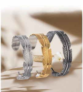Macro detail of feather textured cuff bracelets in silver, gold and black finishes