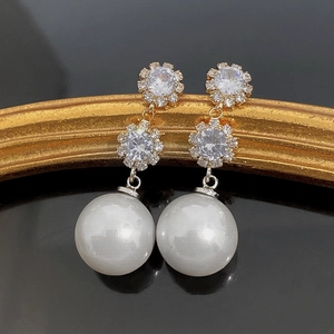 Détail de clous en cristal en forme de fleur et de grandes perles blanches nacrées