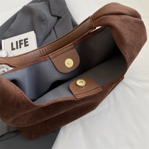 Detail shot of brown suede tote bag featuring internal magnetic clasp and inner fabric lining