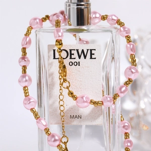 Close-up of pink baroque pearls and gold beads draped on a designer perfume bottle