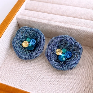 Detailed view of woven blue flower earrings with colorful rhinestones in a velvet jewelry box
