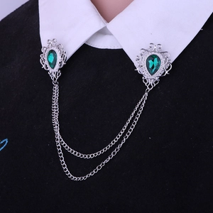 Detail of vintage silver collar pins with emerald waterdrop gems and tassel chains