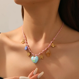 Close-up of woven rope necklace featuring a blue heart pendant and gold floral charms