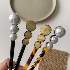 Minimalist pearl hair sticks and gold disc pins set shown in hand for bun hairstyles