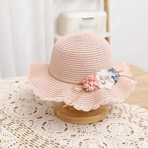 Dettaglio del cappello da sole rosa in paglia con tre fiori 3D e dettagli di perle