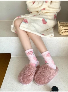 Detail of warm coral fleece crew socks with strawberry pattern and plush home slippers