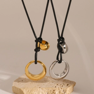 Detail of gold and silver minimalist circular pendants on black woven cord necklaces