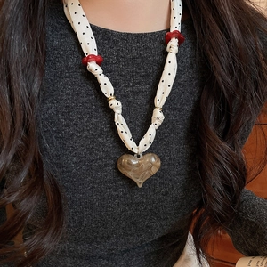 Detail of fabric polka dot chain necklace with brown marble acrylic heart pendant