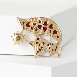 Golden fox brooch with red heart cutouts and star detail on white pedestal