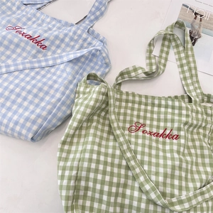 Detail of blue and mint green gingham tote bags with red Sozakka embroidery