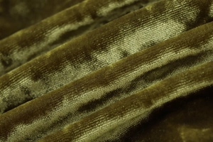 Macro shot of olive green velvet fabric showing pleated texture and soft fiber sheen