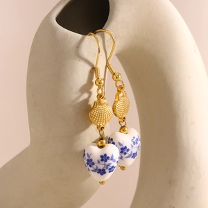 Detail of heart-shaped blue and white porcelain earrings with 18K gold-plated hooks