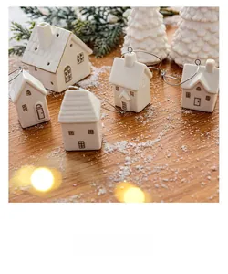 Miniature white ceramic Christmas house ornaments with gold trim on rustic wood table