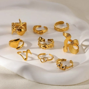 Set of nine textured gold snake and geometric rings with seashell and heart designs
